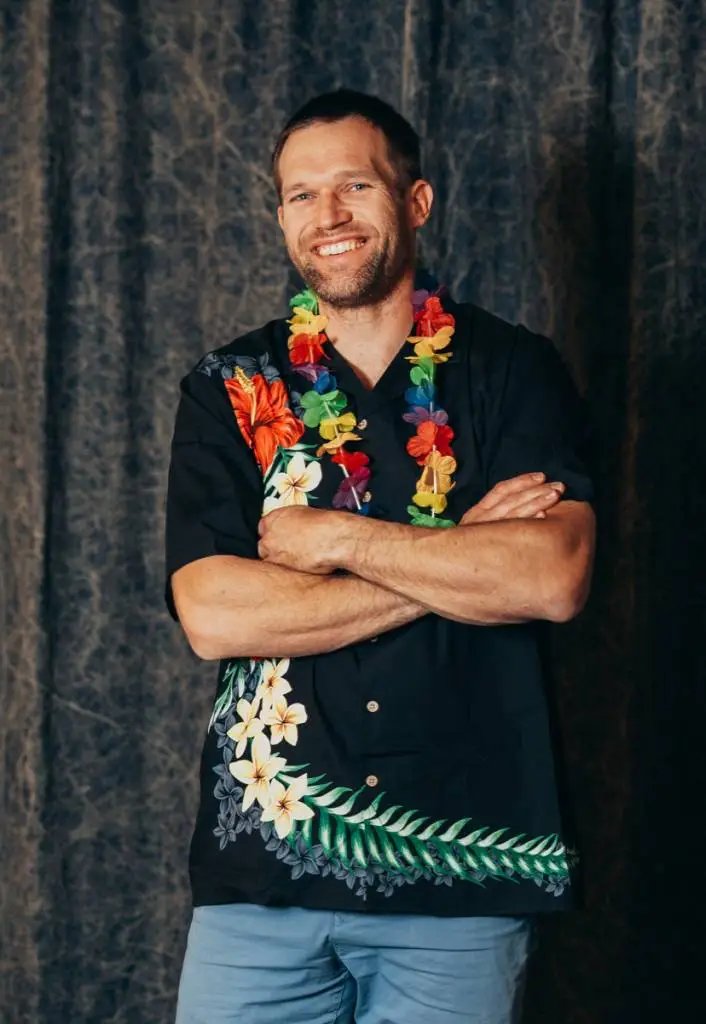 a man wearing a hawaiian shirt with flowers around his neck