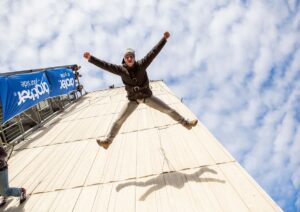 Mann springt wie Hampelmann während House Running an der Fassade und hat Spaß auf einem Sommerfest