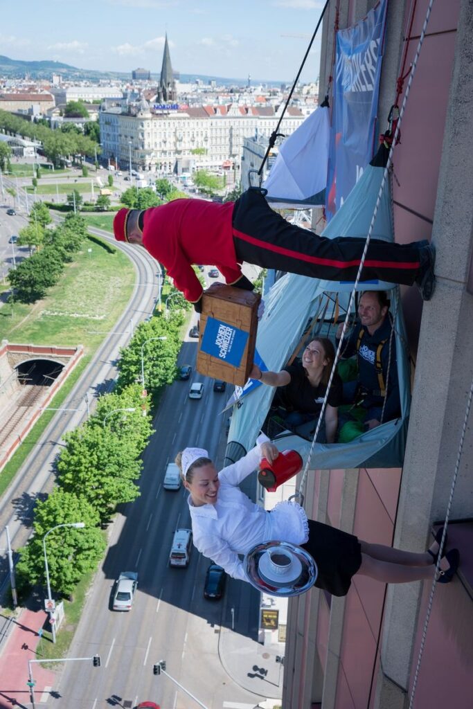Urban Biwaking; 4 Personen gesichert an einer Hauswand in einem Zelt